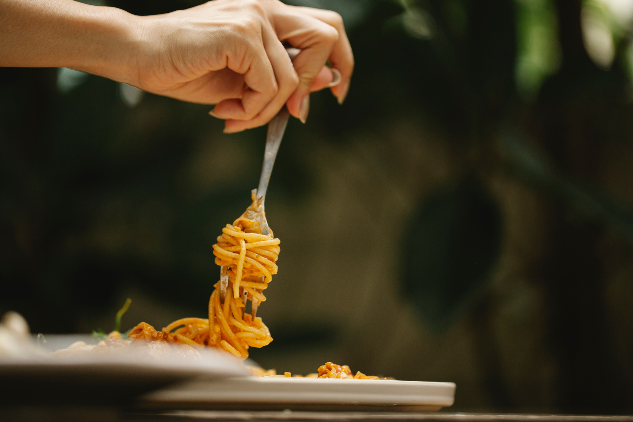 Unrecognizable woman eating appetizing spaghetti in restaurant